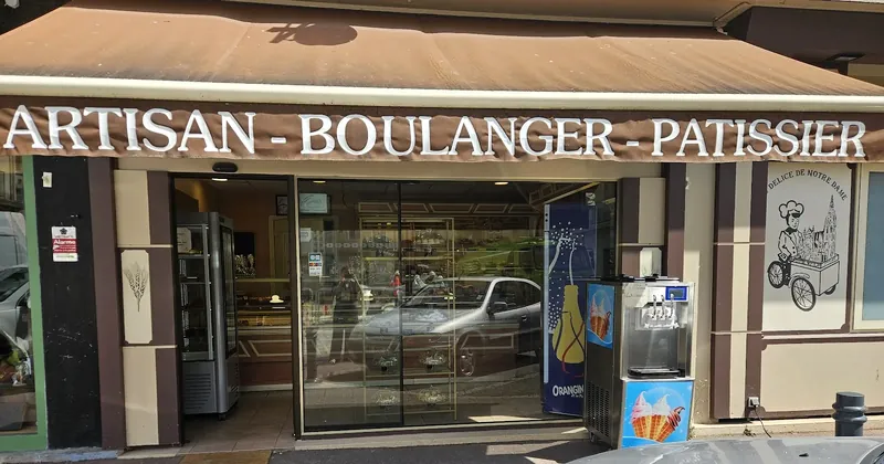 La devanture de la boulangerie vue depuis le trottoir, banne brune et vitrine ouverte.