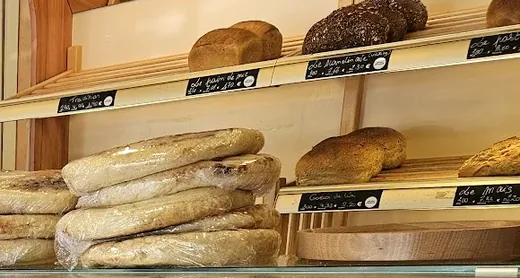 Pains de mie, pains aux céréales et pains de campagne rangés sur les étagères en bois, avec leurs ardoises.