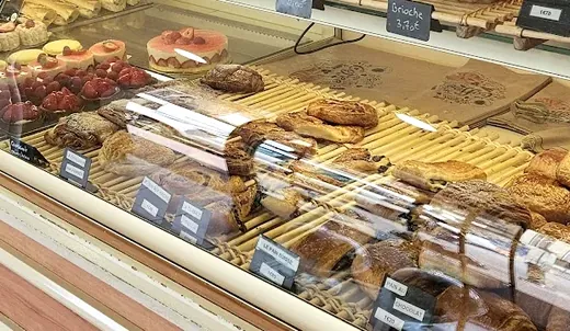 Tartelettes aux fraises et aux framboises et fraisier alignés dans la vitrine.