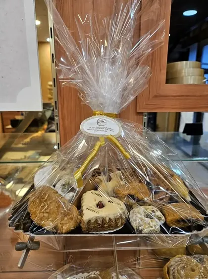 Un plateau de pâtisseries orientales emballé sous cellophane, fermé par un ruban doré et l'étiquette de la boulangerie.