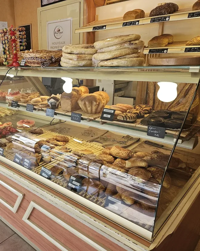 La vitrine réfrigérée de la boutique, sur trois niveaux : tartelettes aux fruits rouges, viennoiseries, brioches et pains au chocolat, chacun avec son ardoise de prix.